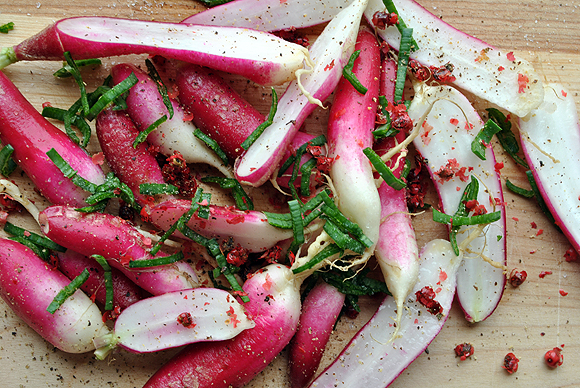 French Breakfast Radishes with pink peppercorns, garlic chives, sea salt, and fresh black pepper before roasting in the oven.